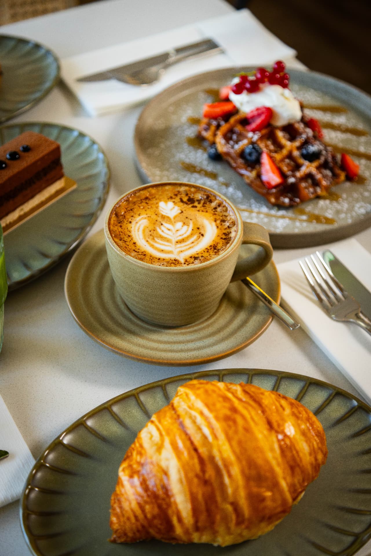 Cappuccino, butter croissant and berry waffles on the table at Tavia Cafe & Restaurant in Dubai Silicon Oasis