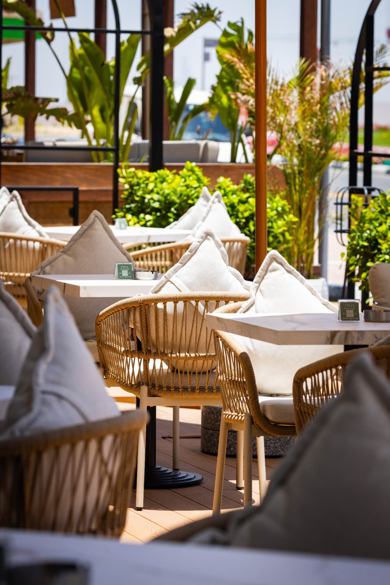 Woven chairs and marble tables on the sunlit terrace at Tavia Cafe & Restaurant in Dubai Silicon Oasis