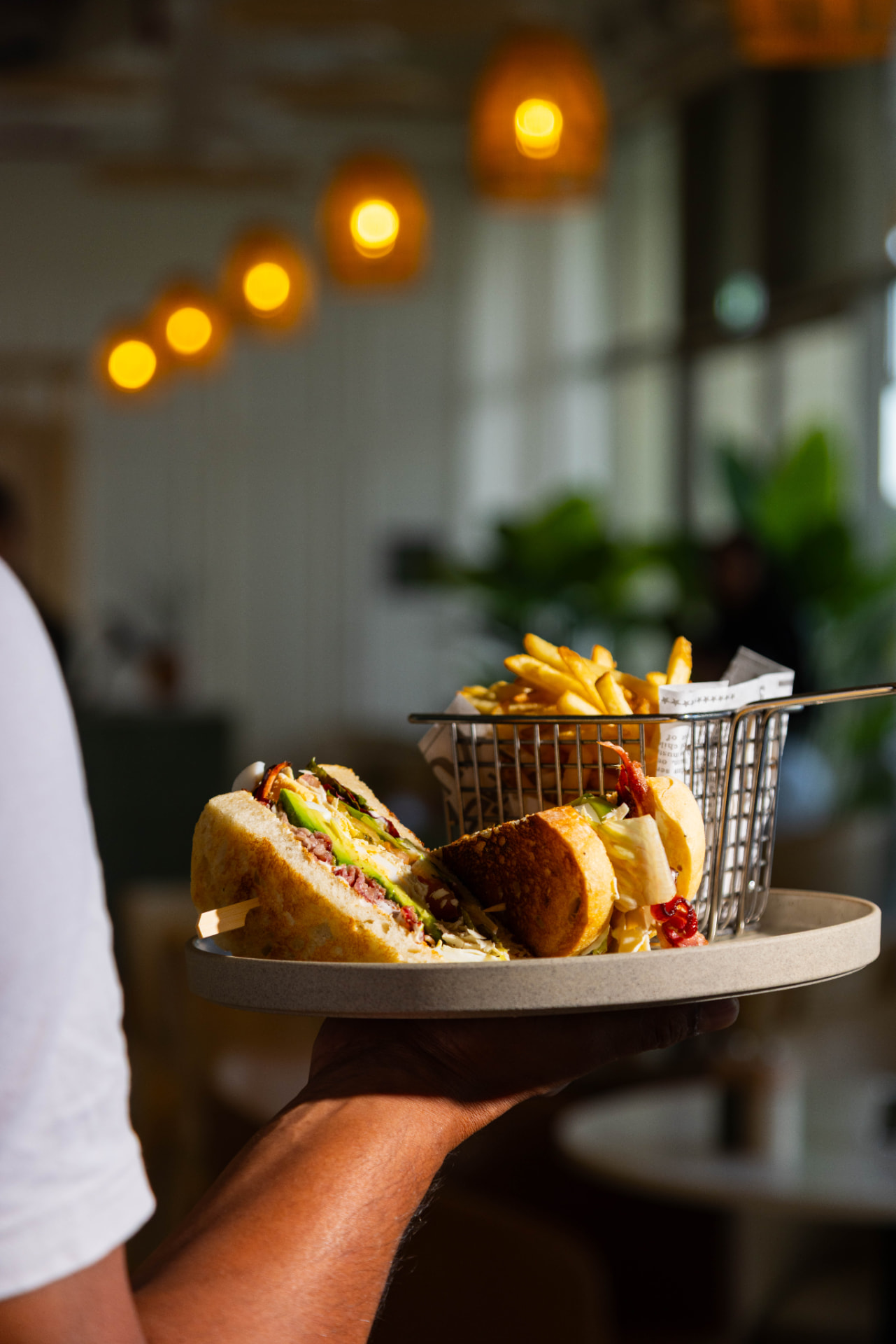 A toasted steak sandwich with avocado and a basket of golden fries at Tavia Cafe & Restaurant in Dubai Silicon Oasis