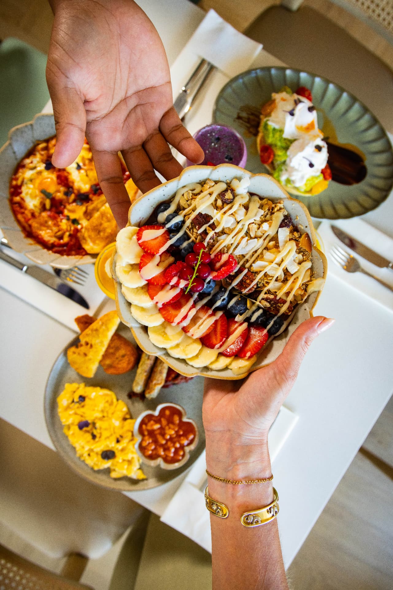 An acai bowl topped with banana, strawberries, blueberries and granola shared over a bright breakfast spread at Tavia Cafe & Restaurant in Dubai Silicon Oasis